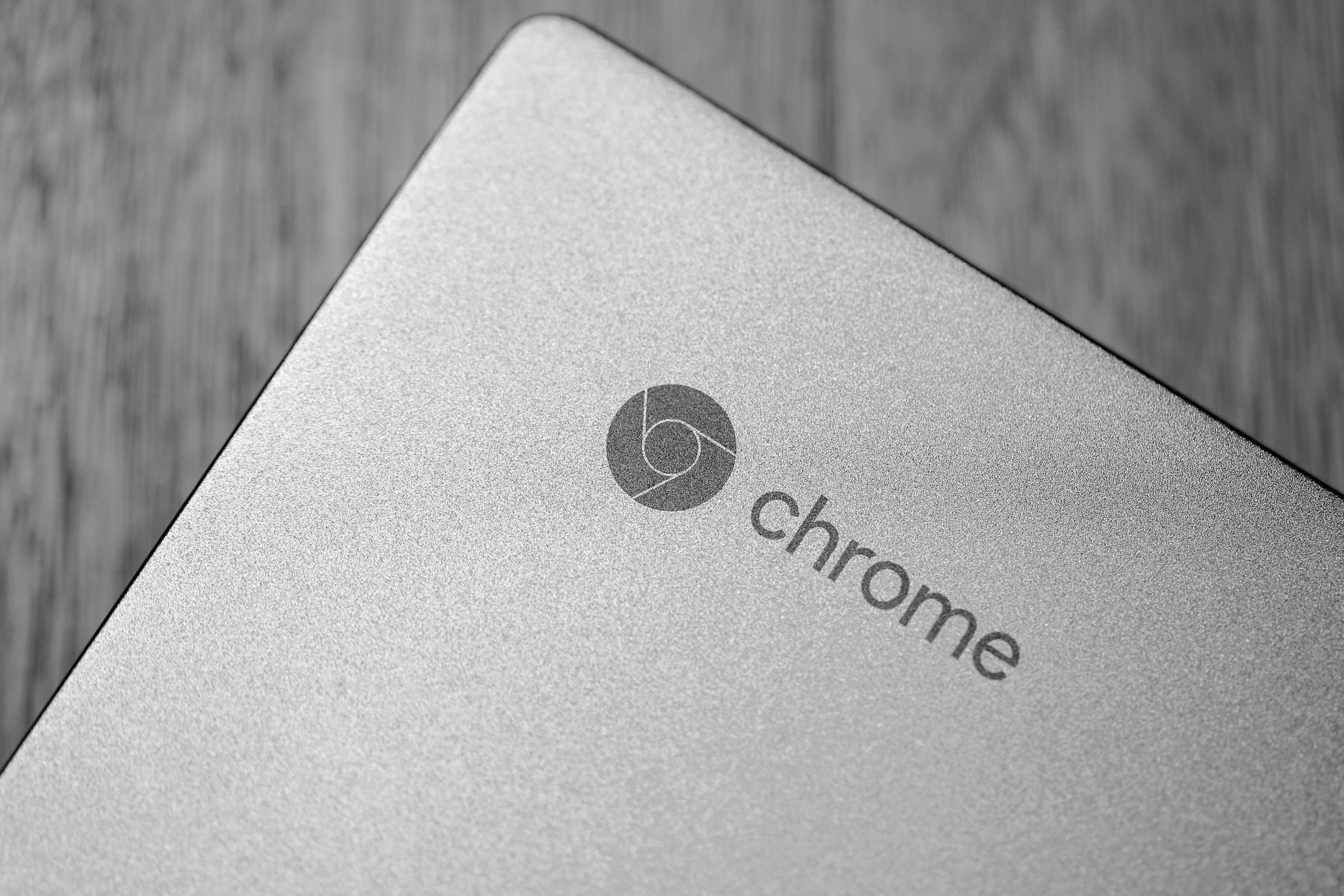 Detailed grayscale image focusing on a Chrome laptop logo, highlighting texture and design.